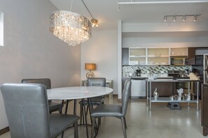 Una cocina moderna con comedor, que incluye una mesa redonda, sillas, una lámpara de araña y un microondas integrado.