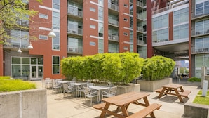 Un patio con mobiliario exterior y un edificio con varios balcones.