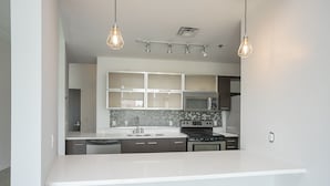 Una cocina moderna con encimeras blancas, armarios oscuros, microondas integrado, estufa y una isla grande.