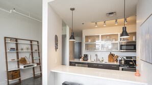 Una cocina moderna con encimeras blancas, armarios oscuros y una isla central con taburetes de bar.