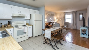 A modern kitchen with white cabinets, a central island, and a dining area with a table and chairs.