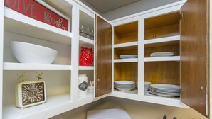 A kitchen with white cabinets, a red 'GIVE Thanks' sign, and various kitchenware.