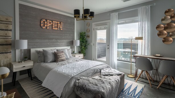 Ein modernes Schlafzimmer mit einem großen Bett, einem Schreibtisch und einem Balkon mit Blick.