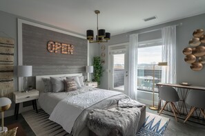 A modern bedroom with a large bed, a desk, and a balcony with a view. - Romantic Studio Getaway with Rooftop Deck (Nashville)