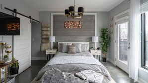 Ein modernes Schlafzimmer mit einem Bett, einem Fernseher, einer Kristallleuchtre und einem großen Schild mit der Aufschrift 'OPEN' an der Wand.