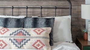 A bed with a headboard, a wall-mounted sign with illuminated letters, and a mounted animal skull. - Rustic Luxe Studio Apartment with Rooftop Deck (Nashville)
