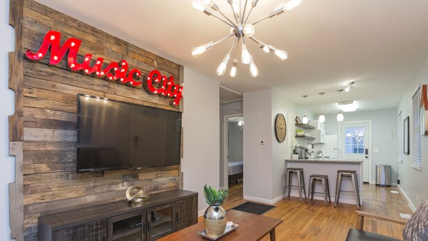 A modern living room with a TV, a coffee table, and a neon sign reading "Music City".