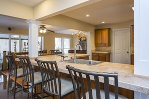 A spacious kitchen with a large island, dark wooden chairs, and a chandelier. - Grand Dream Vacation Home in Nashville 7+ beds! (Nashville)
