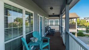 Eine überdachte Veranda mit Stühlen und Tischen, großen Fenstern und Blick auf die Umgebung.