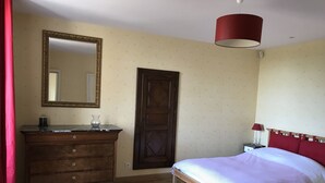 A bedroom with a wooden dresser, a bed with a red headboard, a mirror, and a red lamp on a bedside table. - Charming cottage on the banks of the Mayenne river (Montreuil-Juigné)
