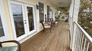 Eine überdachte Veranda mit Holzboden, weißen Geländern und einem Deckenventilator.