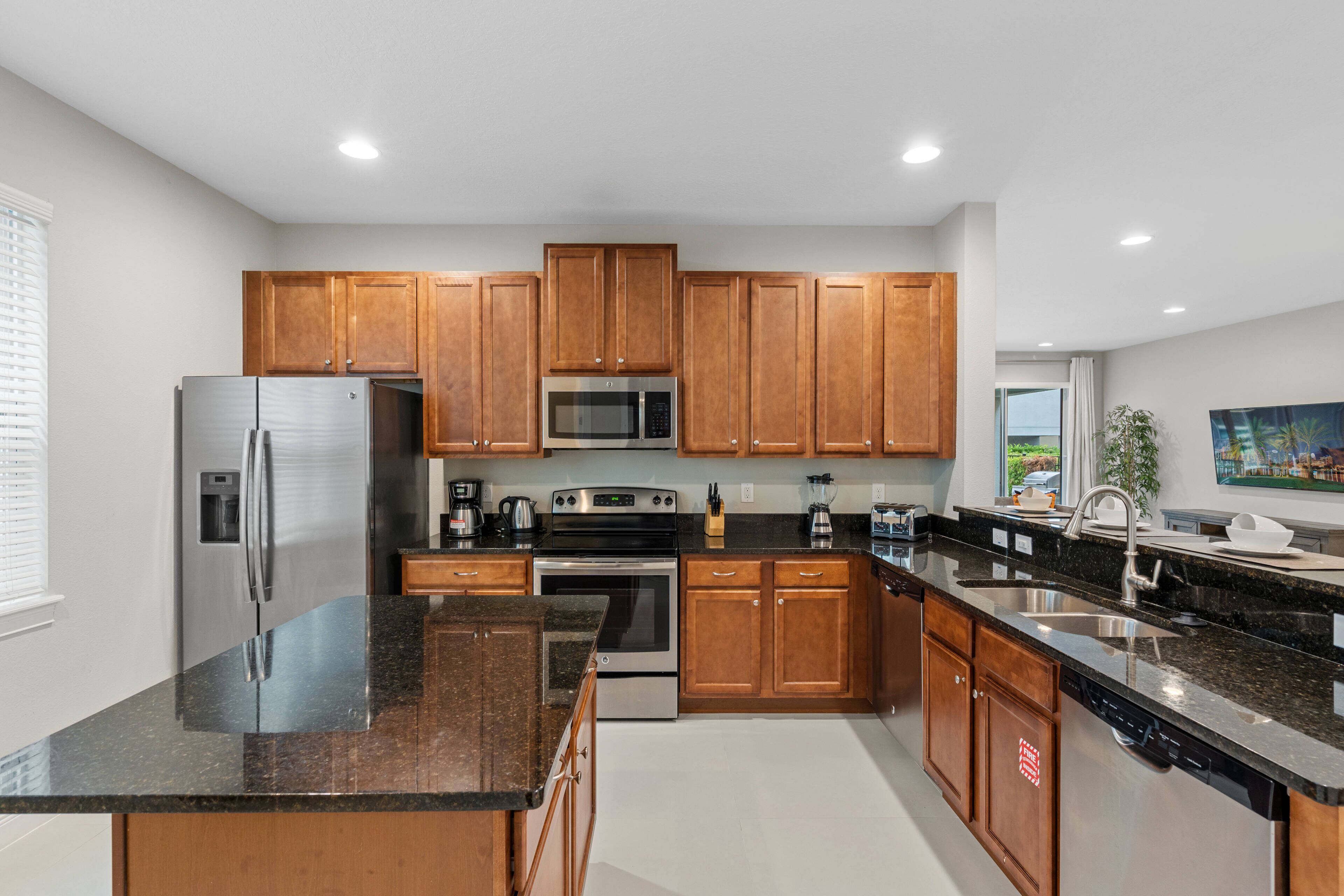 A modern kitchen with wooden cabinets, stainless steel appliances, granite countertops, and a large island.