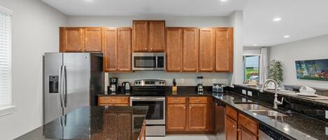 A modern kitchen with wooden cabinets, stainless steel appliances, granite countertops, and a large island.