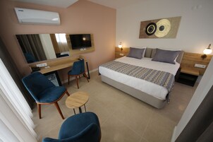 Habitación de hotel con cama, escritorio con silla, televisor y aire acondicionado instalado en la pared.