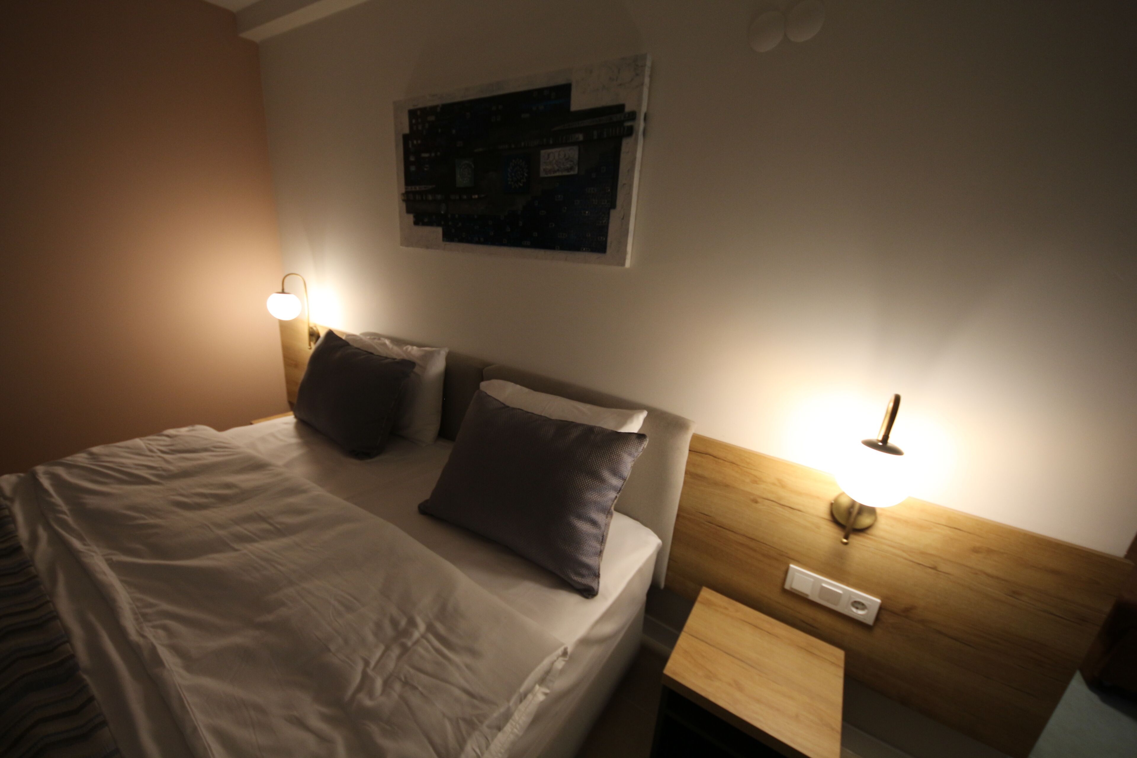 A neatly made bed with pillows, a wall-mounted artwork, and bedside lamps.
