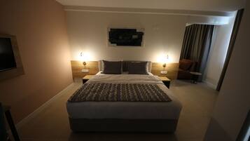 A modern hotel room with a large bed, two bedside tables, a flat-screen TV, and a wall-mounted artwork.