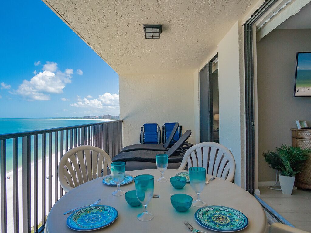 Un balcon avec une table dressée pour deux personnes, donnant sur une plage.