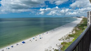 A beach with clear water, a sandy shore, and a few umbrellas.