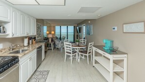 A kitchen with white cabinets, a stove, and a dining area with a table and chairs.