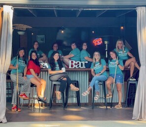 A group of people seated at a bar with a neon sign in the background. - Outdoor PARADISE with Bar,New hot tub2022,NEW POOL 2024, PET FRIENDLY (Hot Springs)