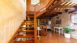 A wooden staircase leading to a loft area with a stone wall and a window.