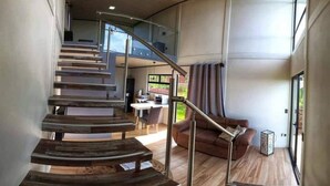A modern interior with a curved staircase, a dining area, and a large window providing natural light.