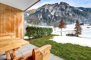 A wooden bench and table in a room with a view of a snowy mountain landscape. - Mountain Lodge by A-Appartements (Brand)