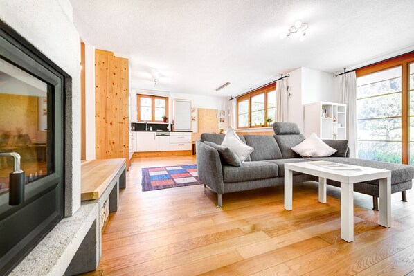 Una sala de estar moderna con un sofá gris, una mesa de centro blanca y suelo de madera.