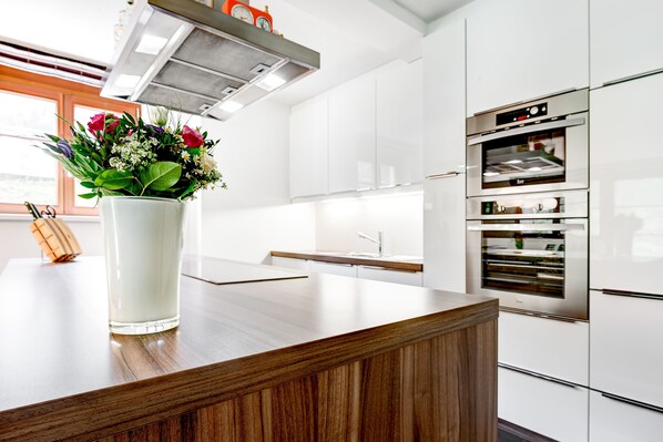 Una cocina moderna con armarios blancos, encimera de madera y horno integrado.