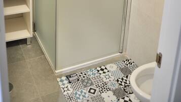 Un baño con cabina de ducha, inodoro y lavamanos.