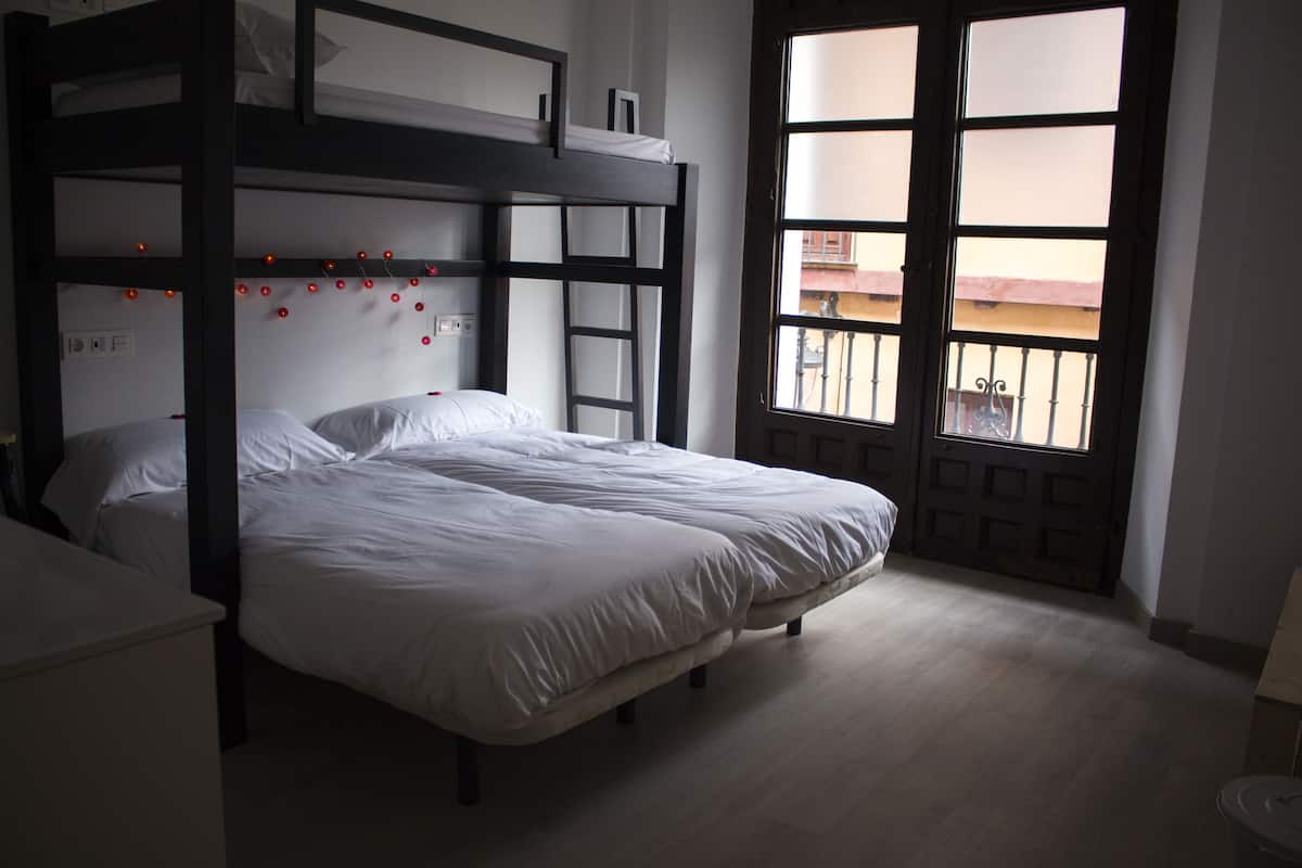 A bunk bed room with a view of the outside balcony through a large window.