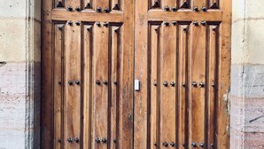 Una puerta doble de madera grande con remaches metálicos, incrustada en un muro de piedra.