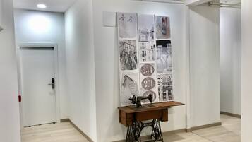 Habitación de hotel con un escritorio de madera, una máquina de coser y una pared con varias fotografías en blanco y negro.