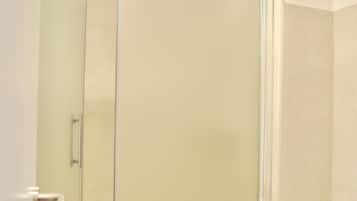 Un bany amb dutxa trencada per vidre, un vàter i un lavabo.