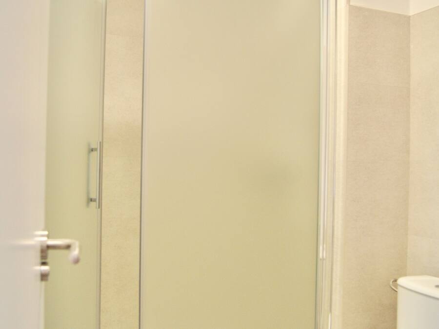 Un bany amb dutxa trencada per vidre, un vàter i un lavabo.