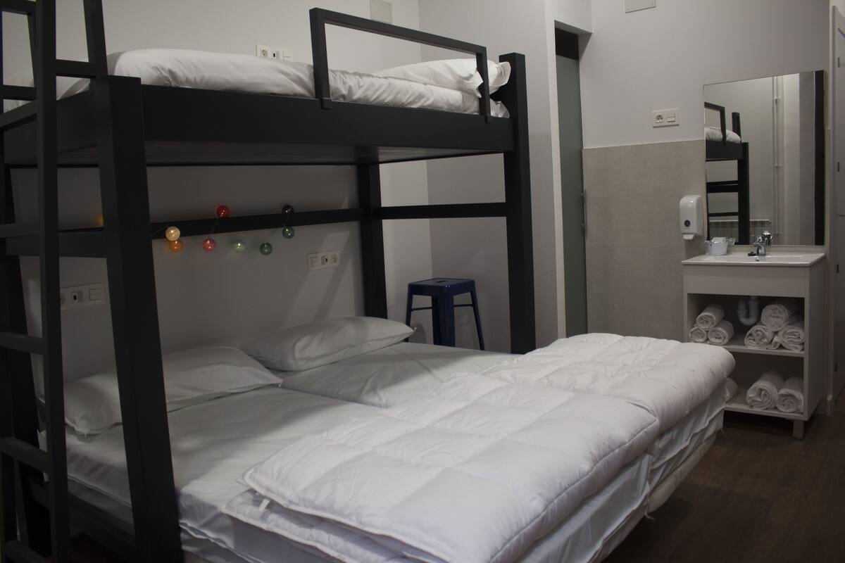 A bunk bed room with a small stool, a sink, and a mirror.