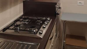 Una cucina compatta con fornelli a gas, un piccolo forno e un piano di lavoro con una cassetta per il pane.