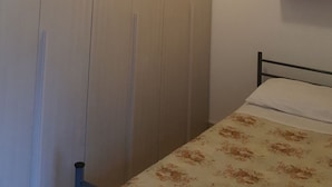 Una camera da letto con un'armadio in legno, un letto con copripiumino floreale e una lampada a sospensione.