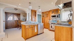 A kitchen with wooden cabinets, a central island, a dishwasher, a stove, and a microwave. - Latitude Change - Luxury Oceanfront Home (daytona beach)