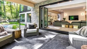 Un espacio exterior moderno con suelo de piedra, mobiliario de mimbre y una pared de piedra.