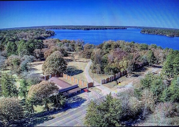 Vista aérea de un parque con un lago, senderos y un pequeño edificio.