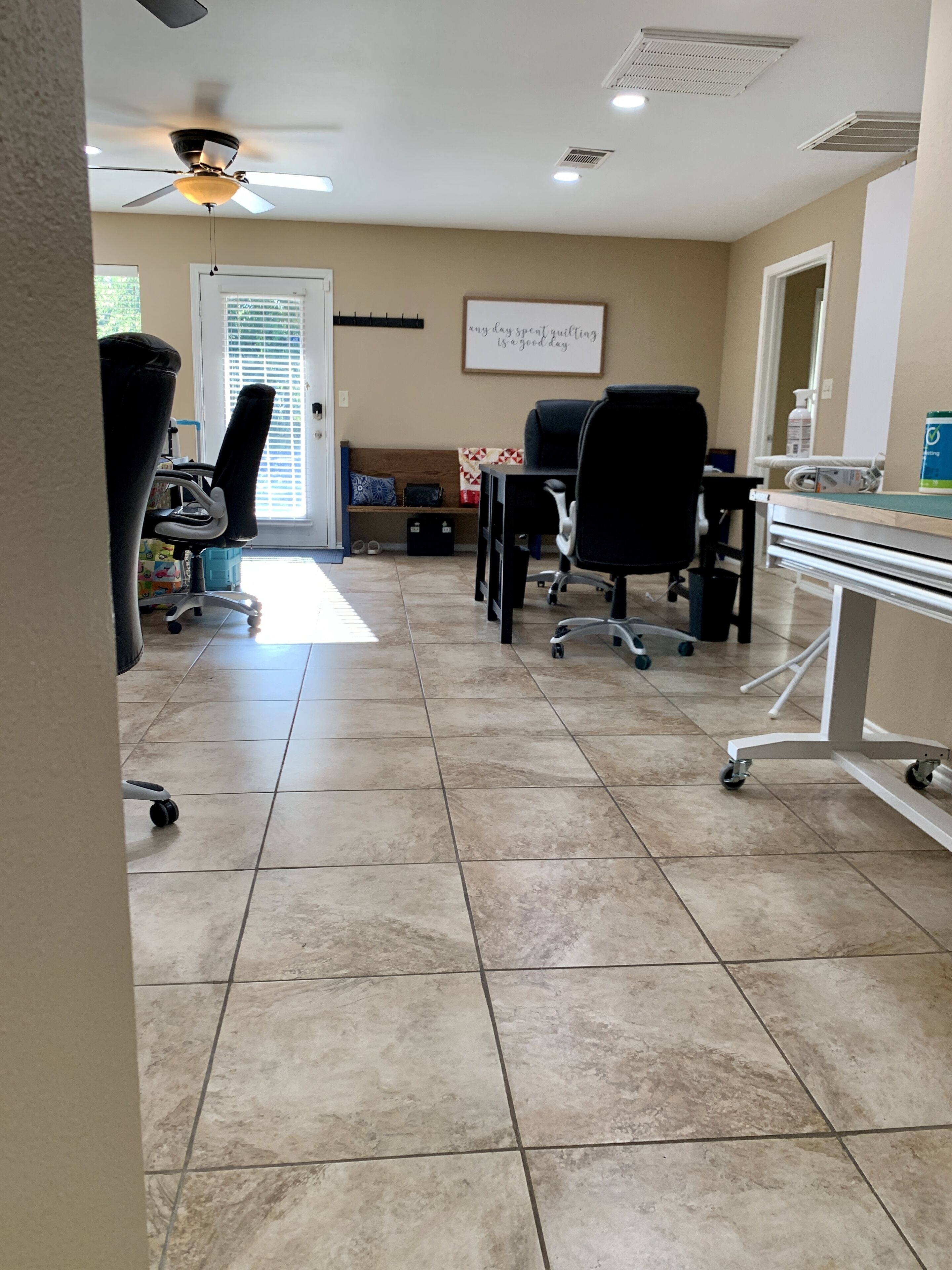 A dental office with two black office chairs, a reception desk, a ceiling fan, and a door leading outside.