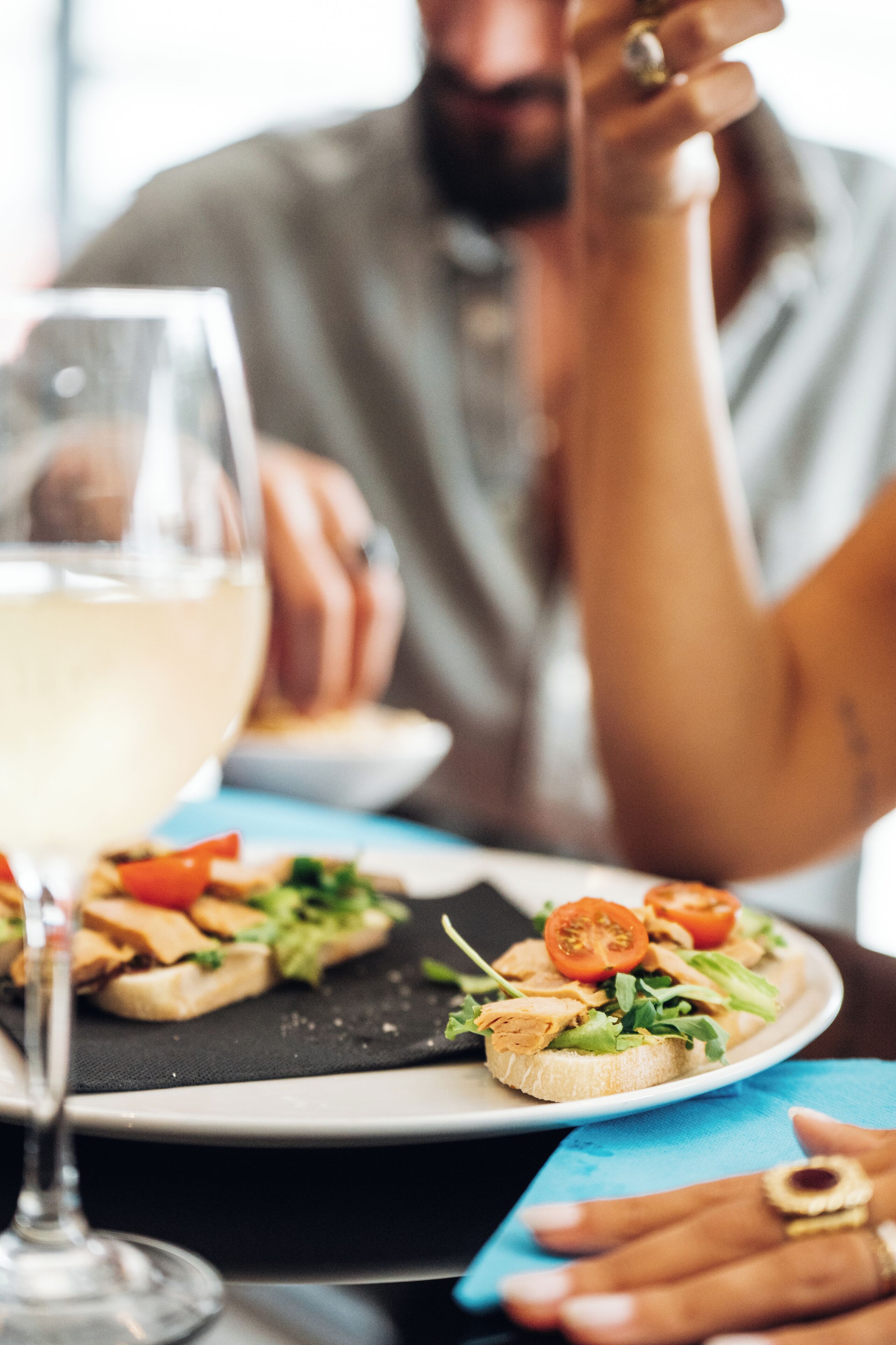 Una mesa de comedor con un plato de comida y una copa de vino blanco.