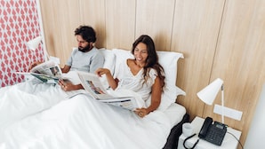A bedroom with a wooden headboard, a bedside table with a lamp, and a phone.
