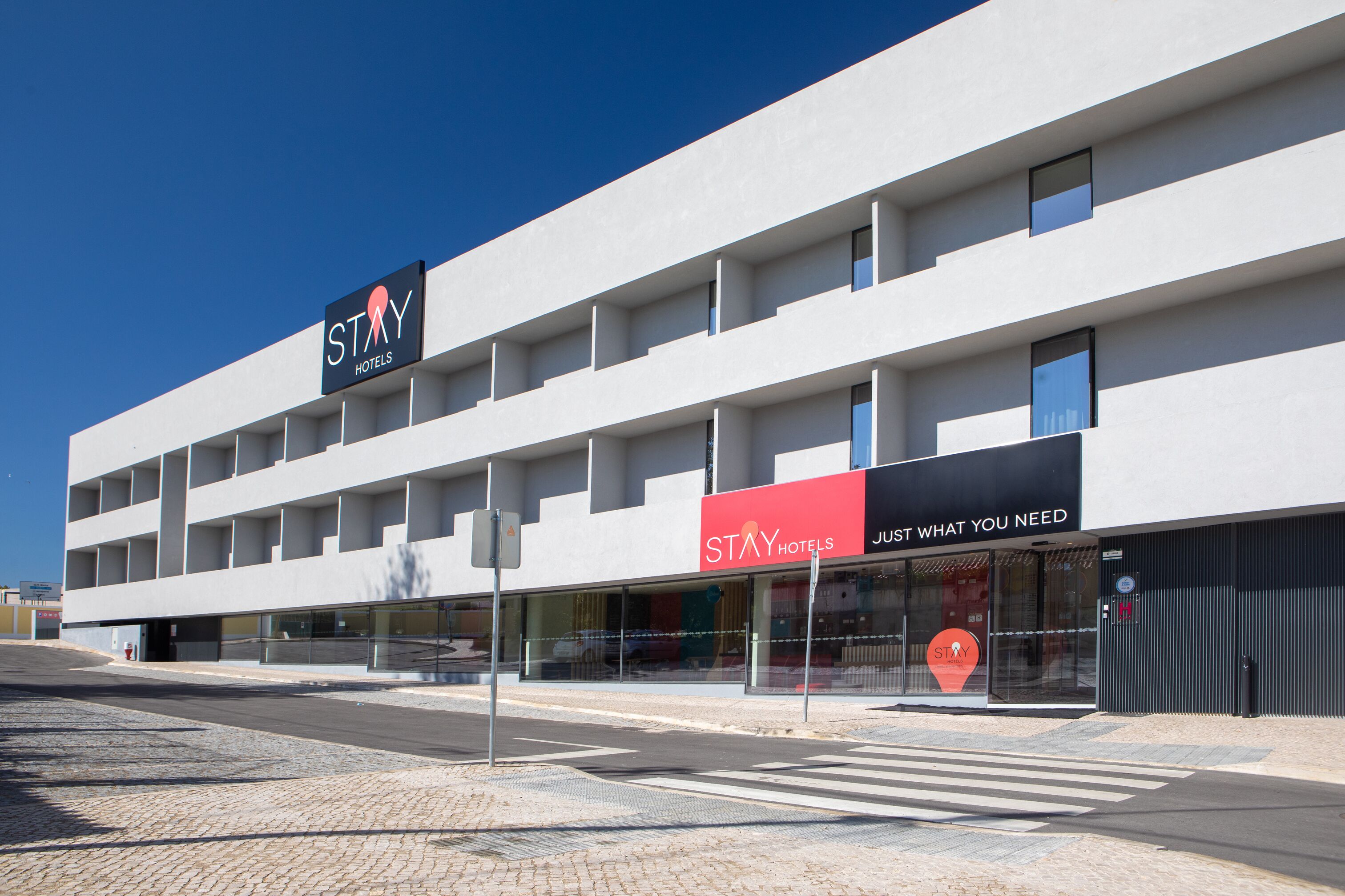 Een modern hotel met een vlakke gevel, meerdere balkons en grote ramen.