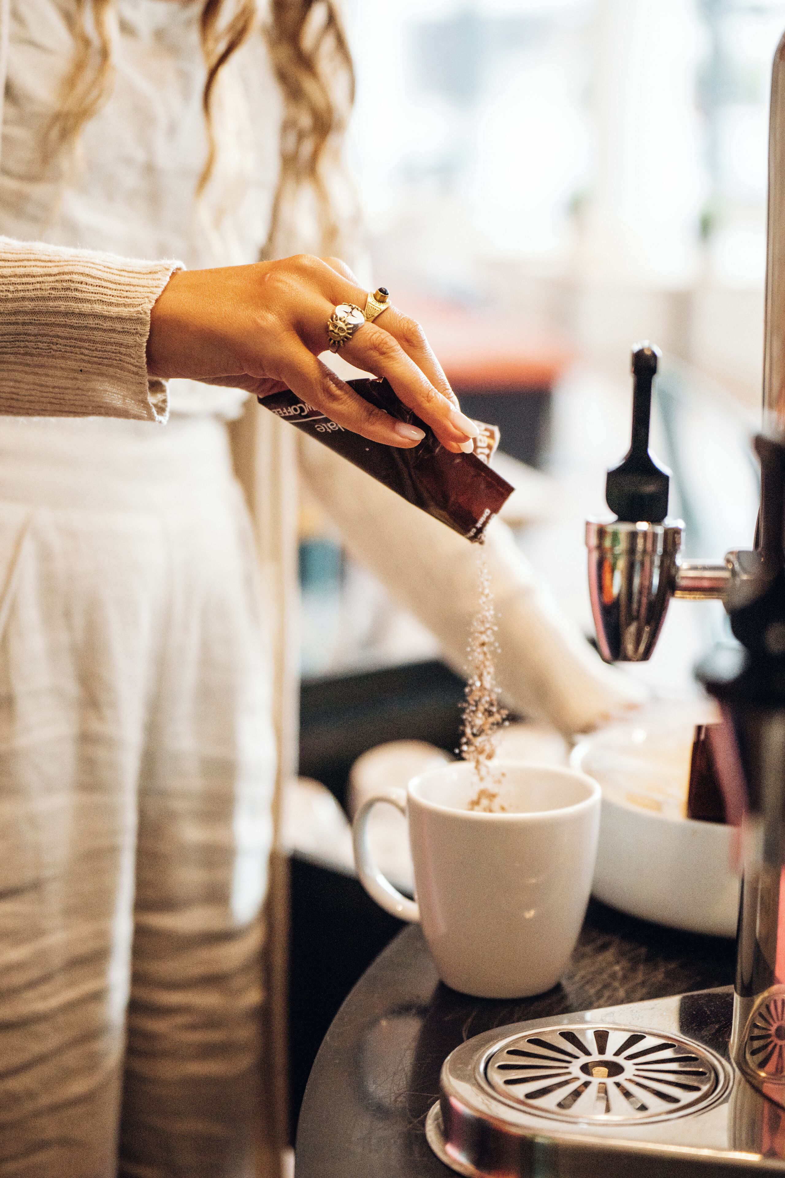 Une personne verse du café moulu dans une tasse.