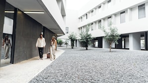 A modern building with a gravel courtyard, large windows, and minimalistic design.