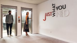 An elevator interior with a wall sign reading "JUST NED".