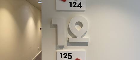 Un pasillo con un cartel en la pared que indica los números de habitación 120, 124, 125 y 150.