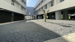 A modern building with a courtyard, featuring a gravel ground and a few small trees.